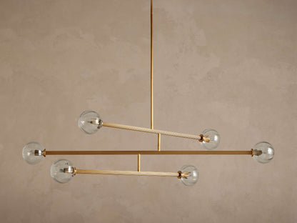 Front view of a modern Linear Gold and Glass Chandelier with five clear glass globes and reeded gold-colored rods.