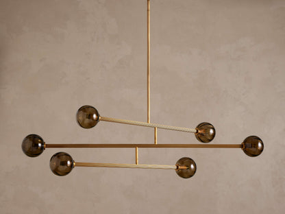 Modern chandelier with a brass frame and five smoky brown glass globe shades, suspended from above.