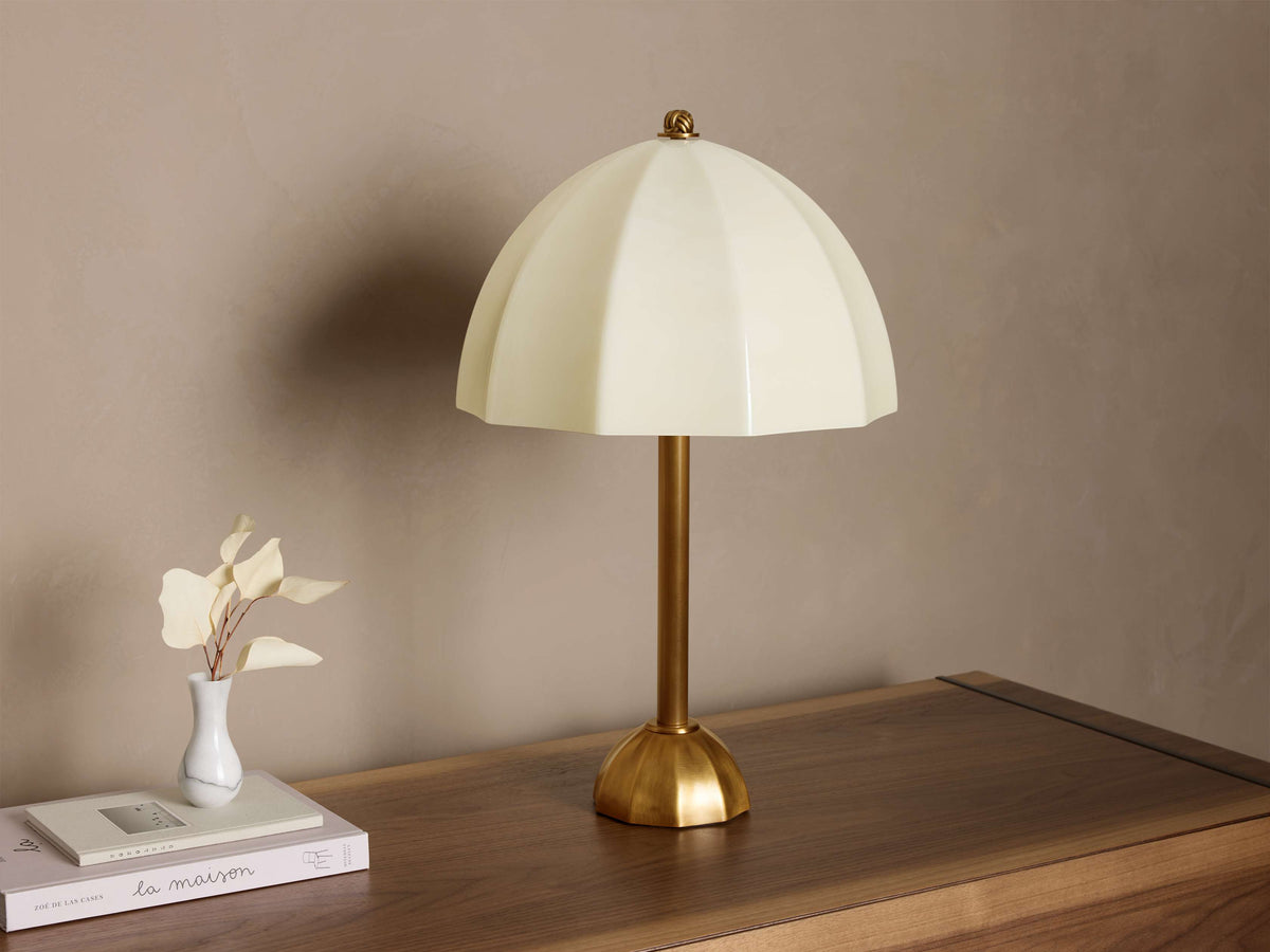 Close-up of an antique brass knot finial on a glowing off-white lamp shade.