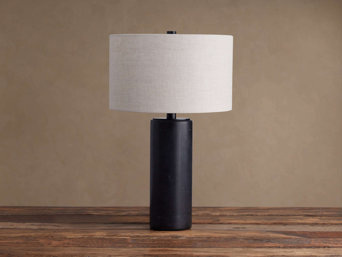 Close-up of the Brixton Table Lamp's cylindrical black marble base with white veining, topped by a matte black metal disc.