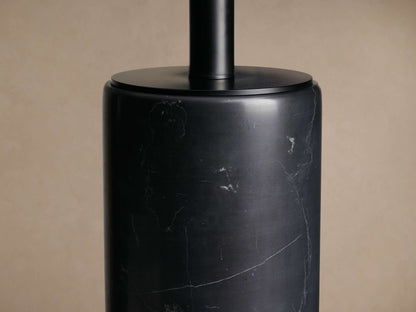 Brixton Table Lamp with a dark cylindrical marble base and a black fabric drum shade, standing on a rustic wooden table.