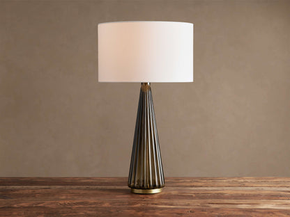 Elisabetta Table Lamp: upright, white linen shade, smoky fluted glass base, brass accent, sitting on a wooden table.