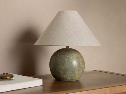 Front view of a table lamp featuring a spherical green marbled base and a light beige linen tapered lampshade.