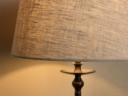 Close-up of the textured gray fabric shade and dark bronze-finished base of the Winslow Table Lamp, glowing with light.