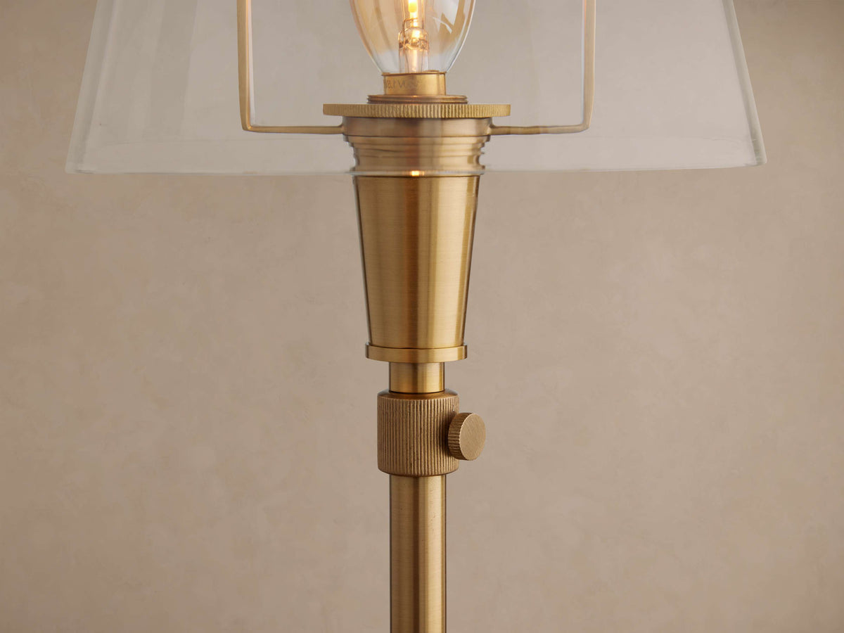 Close-up of Candice Table Lamp in brass. Clear shade, exposed filament bulb, and a textured brass rotary switch.